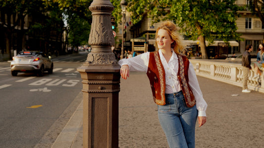 Vrouw in Parijs gekleed in bohemian style met een witte blouse en een suède gilet.